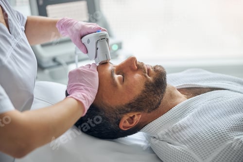 Preview: Doctor cosmetologist treating male skin with laser device
