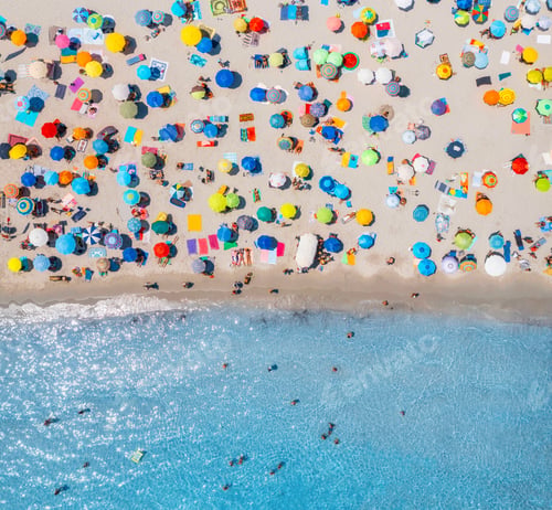 Preview: Aerial view of umbrellas on sandy beach, people in blue sea