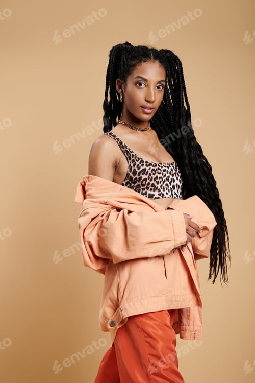 Preview: A young woman showcases trendy fashion with confidence against a warm background