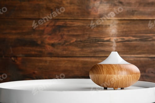 Preview: Modern essential oil diffuser on white table against wooden background. Space for text