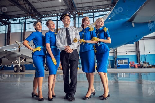 Preview: Smiling cheerful four stewardesses with handsome pilot in stylish uniform