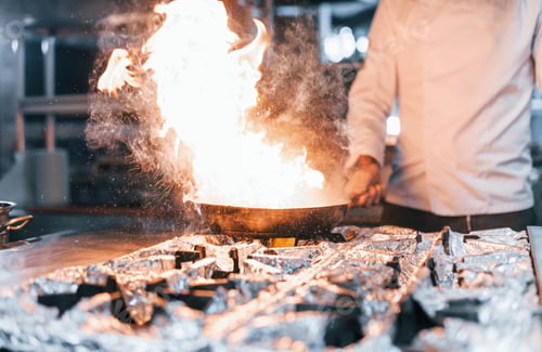 Preview: Frying pan is on fire. Chef in white uniform cooking food at kitchen. Busy day at work