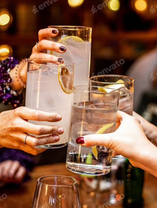 Preview: Vertical shot of girlfriends having cheers on their cocktail drinks