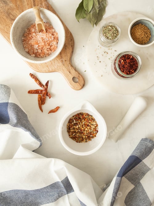 Preview: Various dry spices and dry vegetables in mortar and glass jars flat lay on kitchen table