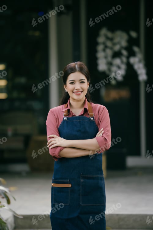 Preview: A woman in a blue apron stands with her arms crossed