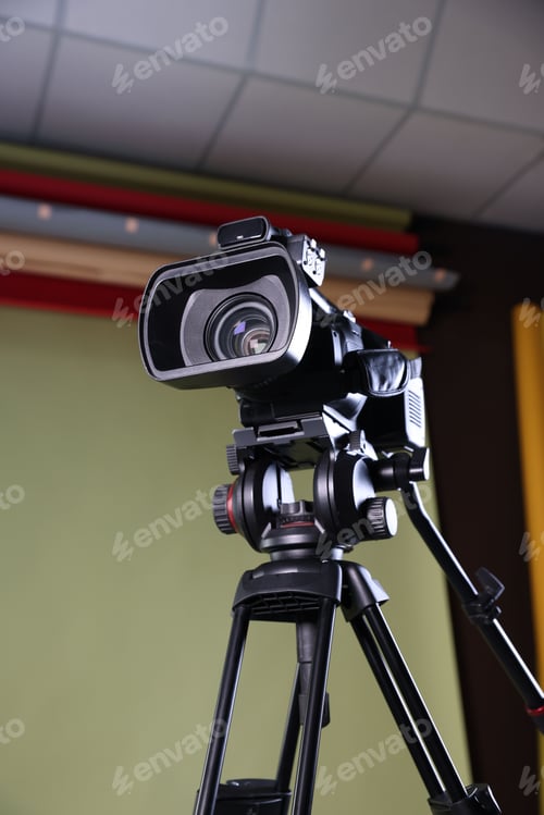 Preview: Modern video camera with tripod in studio, low angle view