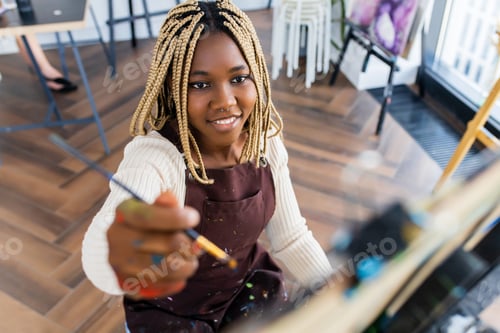 Preview: latino hispanic woman paints on canvas with oil colors in workshop