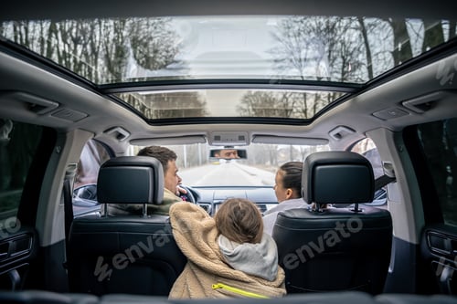 Preview: Rear view. Little girl sitting in back seat of car during family trip.