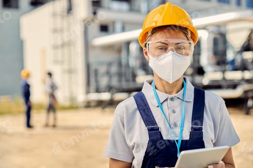 Preview: Female building contractor with digital tablet wearing face mask at construction site.