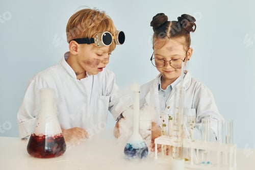 Preview: Girl with boy working together. Children in white coats plays a scientists in lab by using equipment