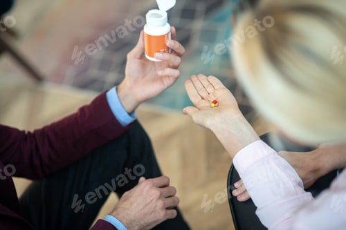 Preview: Top view of blonde stressed woman taking antianxiety pills