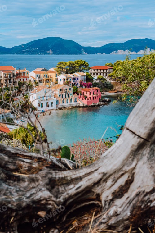 Preview: Assos village in Kefalonia, Greece. Calm blue bay water and colored traditional houses. Old snag in