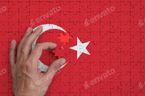 Preview: Turkey flag is depicted on a puzzle, which the man's hand completes to fold.