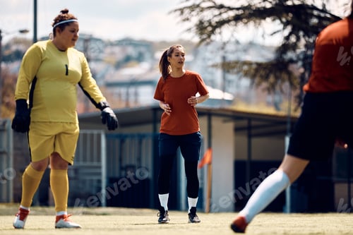 Preview: Female soccer team having sports training on playing field.