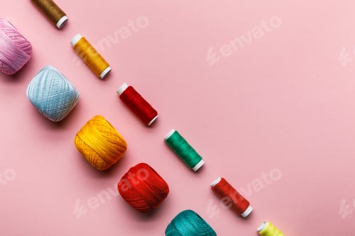 Preview: top view of colorful knitting yarn balls and thread coils on pink with copy space