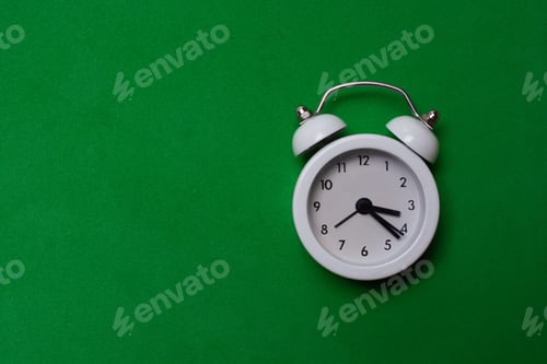 Preview: Closeup shot of a white clock on a green surface with a copy space