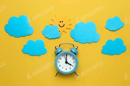 Preview: Blue round alarm clock, sun and clouds on the yellow background.