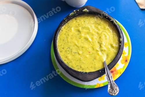 Preview: High angle shot of guacamole in a bowl with a spoon on a blue surface