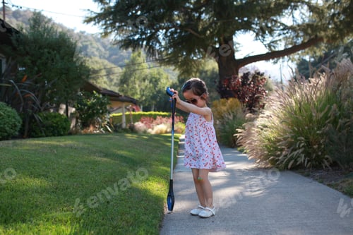Preview: Young girl using a grabber tool to pick up trash in the neighborhood