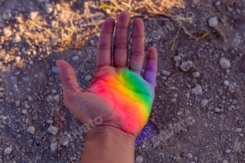 Preview: Human hand with colorful rainbow reflection on her. Sunset outdoors. Pride