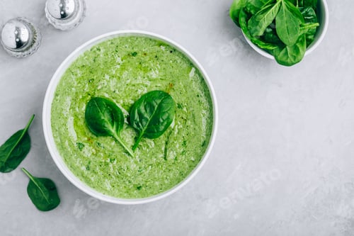 Preview: Green creamy spinach soup on a gray concrete background.