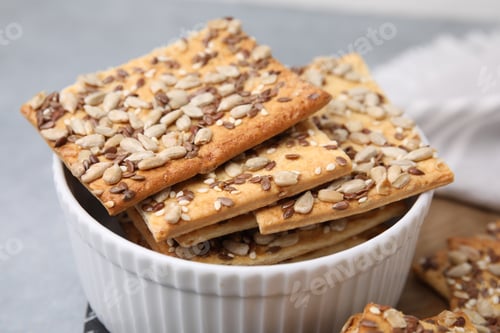 Preview: Cereal crackers with flax, sunflower and sesame seeds in bowl on grey table, closeup