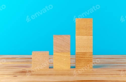 Preview: Stacked wooden blocks on wooden desk against blue background