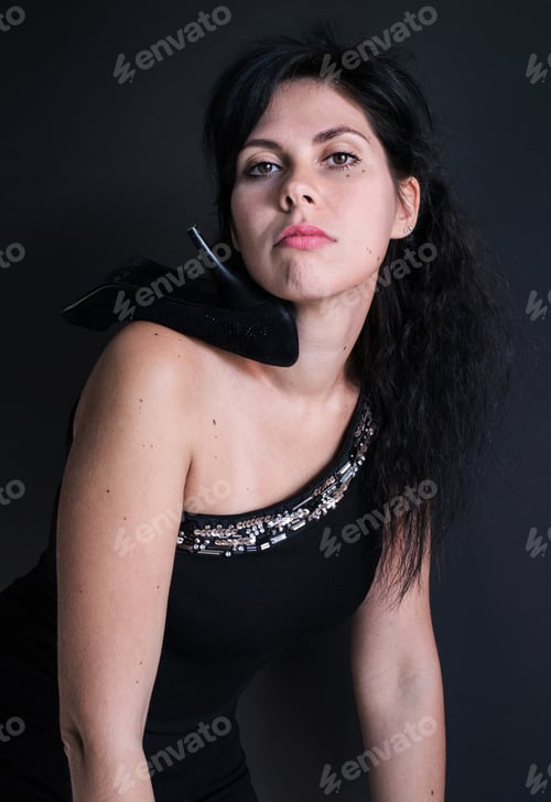 Preview: Photo Portrait Of A Dark Haired Model In Black Dress On One Shoulder And A Shoe With A Heel
