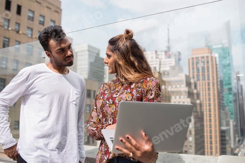 Preview: Woman showing laptop to colleague while standing at restaurant