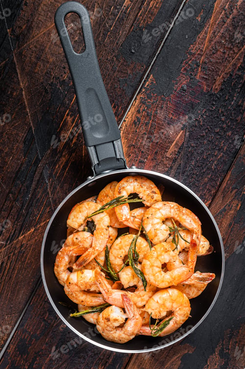 Preview: Fried with butter and garlic prawns shrimps in a skillet. Wooden background. Top view