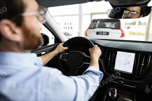 Preview: Businessman test driving new car with navigation system in dealership