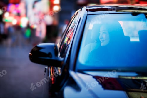 Preview: Serene woman looking through car window at the city nightlife