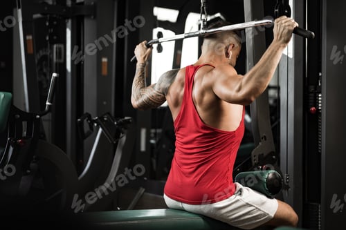 Preview: Back view of a man bodybuilder exercising in a gym