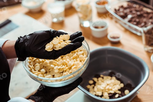 Preview: cropped view of chocolatier holding white chocolate chips in hand