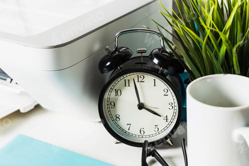 Preview: Clock placed on a desk beside a plant, printer, and mug in a workspace filled with productivity