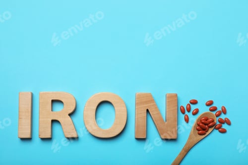 Preview: Word Iron and pills on light blue background, flat lay with space for text. Anemia treatment