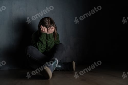 Preview: Sad little girl, alone in darkness, sitting and and covering face