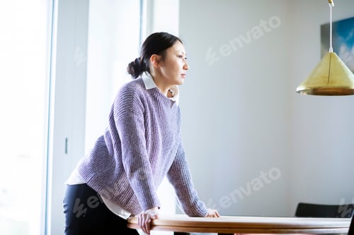 Preview: Pensive woman standing at table