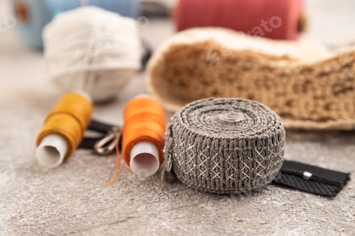 Preview: Sewing accessories: scissors, thread, thimbles, braid on brown concrete background. Side view