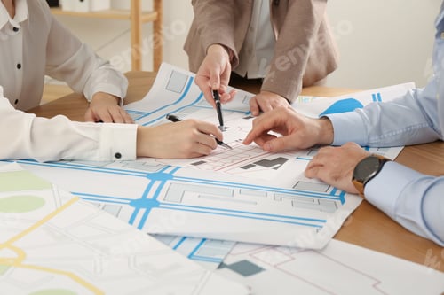 Preview: Professional cartographers working with cadastral map at table in office, closeup