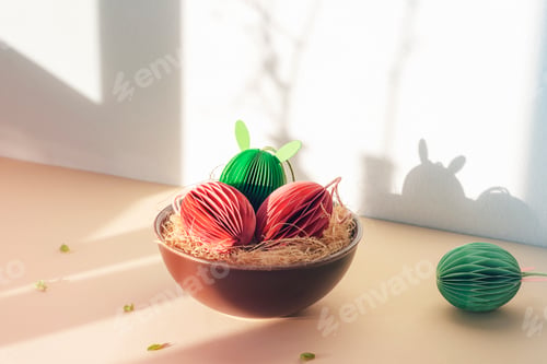 Preview: Paper Easter eggs with bunny ears in bowl in sunlight. Closeup