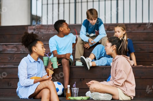 Preview: Two intercultural schoolgirls chatting while one of them having soda