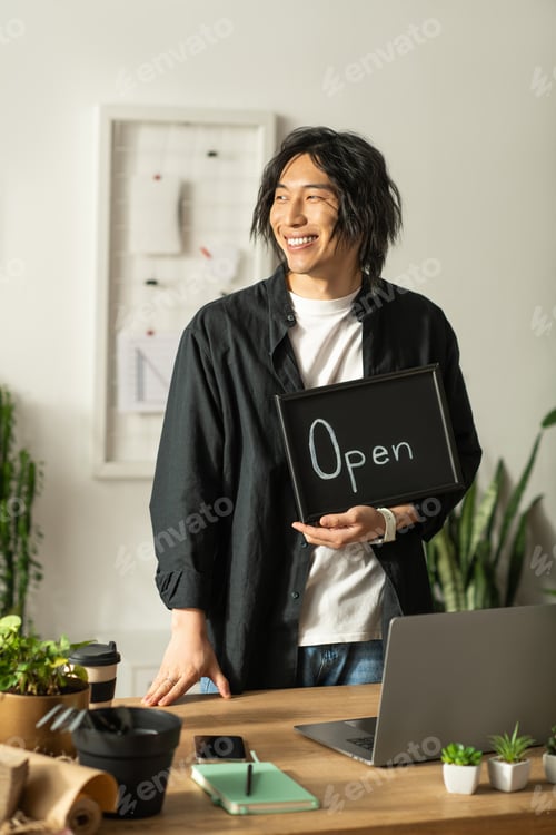 Preview: Joyful Asian florist welcomes customers with a cheerful smile in a bright shop