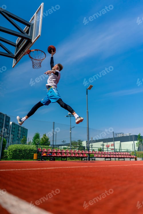Preview: Tall guy basketball player jumps to the hoop with the ball in his hand to score spectacular dunk