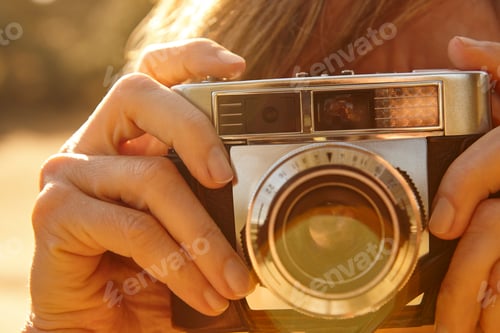 Preview: Woman taking pictures with vintage camera. Back light. Travel background.