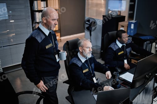 Preview: Middle Aged Security Guards Monitoring Surveillance Cameras in Control Room
