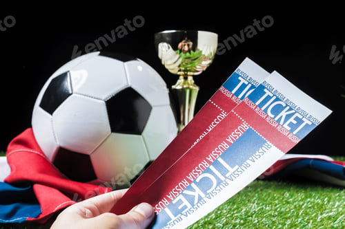 Preview: Fans hold tickets for a soccer match with a trophy and ball in the background