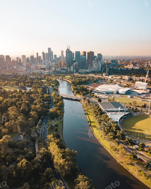 Preview: Drone vertical shot of the Melbourne cityscape with a river and green trees on a sunny day