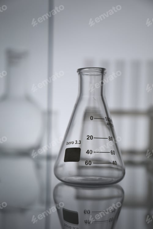 Preview: Empty flask on mirror surface against light background. Laboratory equipment