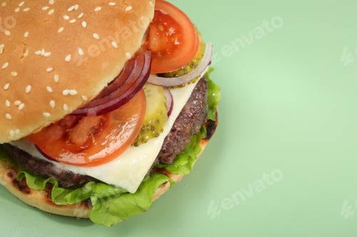 Preview: Burger with delicious patty on green background, closeup. Space for text
